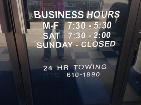Business hours in white on glass door